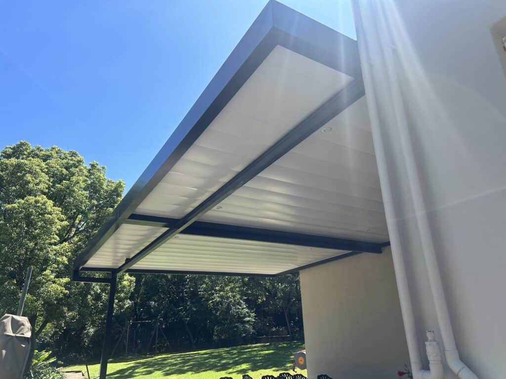 Modern outdoor architectural pergola with sleek black frame and white roof panels.