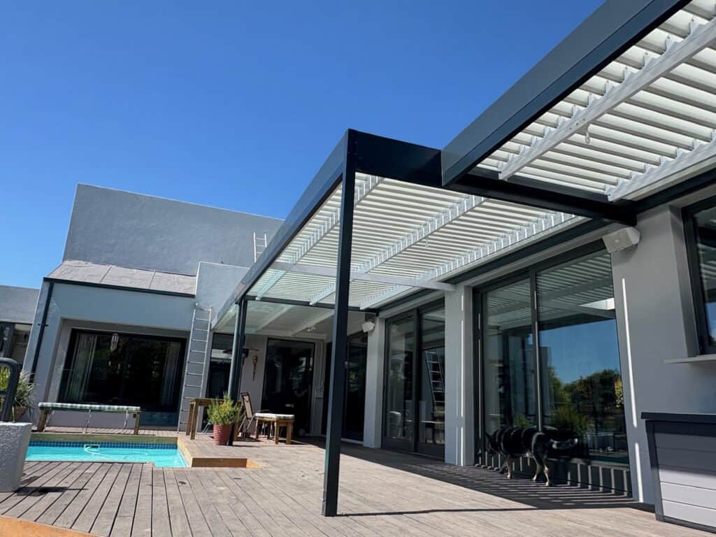 Dual-action louvre awning providing natural ventilation and UV protection for a patio.